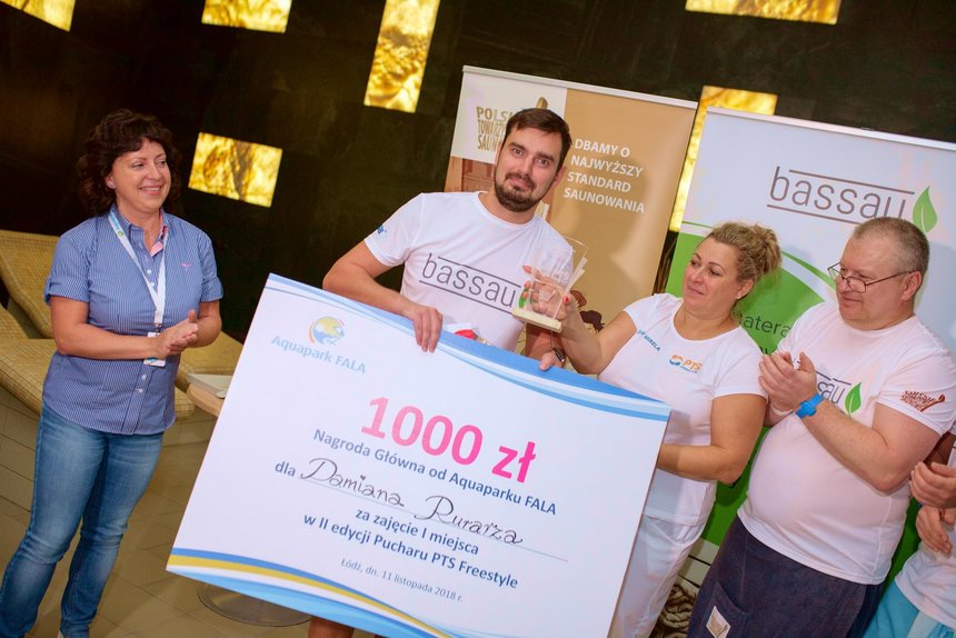 Zwycięzca turnieju Damian Rurarz pozuje z pamiątkową tablicą ukazującą nagrodę specjalną Aquaparku FALA, czyli 1000 złotych. Po lewo przedstawicielka Aquaparku, po prawo sędziowie turnieju.