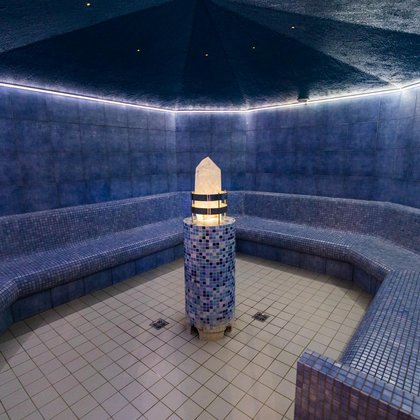 Wnętrze krystalicznej sauny parowej, w centralnym punkcie stoi podświetlany kryształ na ceramicznym podeście. Dookoła sauny dostępne są ceramiczne siedziska. 