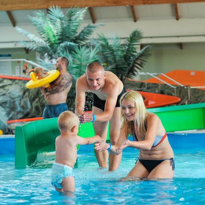 A family of three: mom, dad and small son in one of the water playgrounds. 