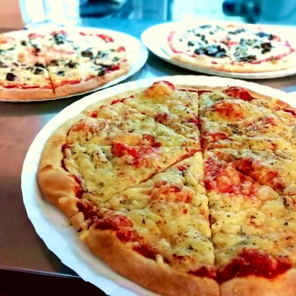 Trzy świeżo upieczone pizze. Na pierwszym planie klasyczna pizza Margherita.. 