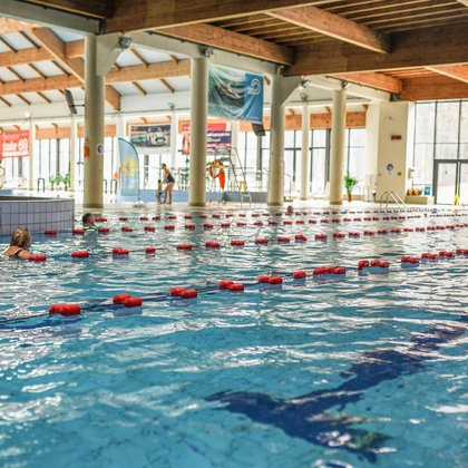 Indoor sports pool. There are several swimmers on the tracks.