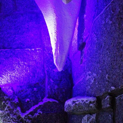 Wnętrze groty śnieżnej - zbliżenie na jeden ze stalaktytów oświetlonych w kolorze fioletowym. 