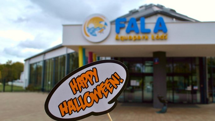 Wejście główne do Aquaparku FALA. Na pierwszym planie biała tabliczka z czarnym obrysem i pomarańczowym napisem Happy Halloween. 