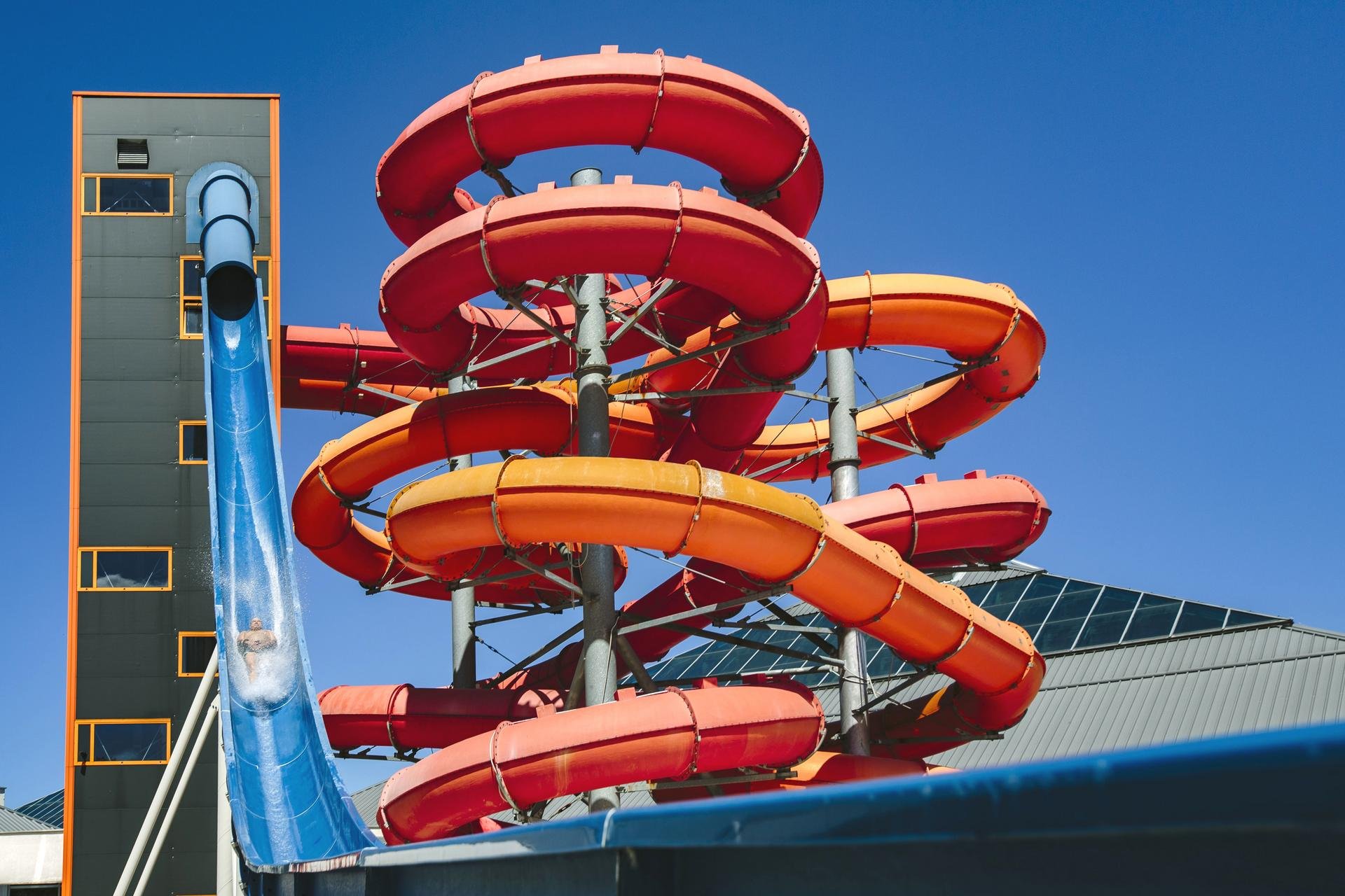 Wieża zjeżdżalni, na pierwszym planie niebieska zjeżdżalnia Kamikaze, a za nią pełne zakrętów rury czerwonej i pomarańczowej MegaZjeżdżalni. 