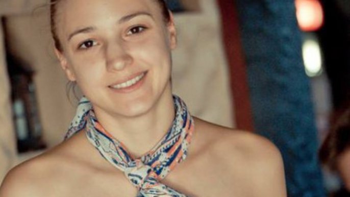 Saunamistrzyni Monika Klag. Ujęcie portretowe. Młoda kobieta o ciemnych oczach z uśmiechem spogląda w obiektyw. Ma na sobie kolorowy hammam zawiązany na szyi. 