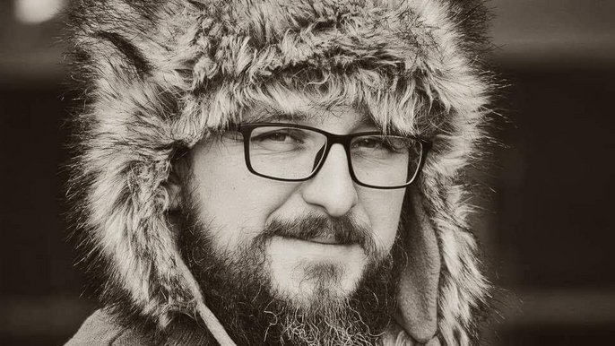 Saunamistrz Marek Olszewski - zdjęcie portretowe mężczyzny w okularach i z brodą. Ma na sobie futrzaną czapkę. 