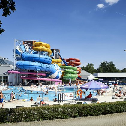Panorama of the external part of the Pool Zone on a sunny day. In the background there are colorful MegaSlides. 