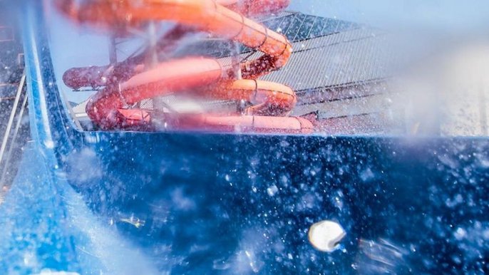 Zdjęcie z hamowni niebieskiej zjeżdżalni Kamikaze - rozpryśnięta woda całkowicie zasłania zjeżdżalnię i megazjeżdżalnie w tle. 