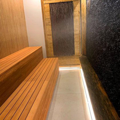 Wnętrze tężni solnej, po lewo dwie drewniane ławy, naprzeciw drzwi i po prawej stronie tężnia w postaci drewnianych gałązek, po których spływa solanka ciechocińska. 
