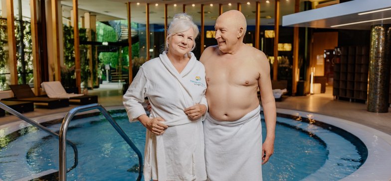 2 seniorów pozuje na tle strefy saun na Fali